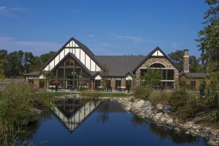 Beacon Hill at Eastgate senior living community exterior with outdoor patio dining area in background and the landscaped pond area in the foreground