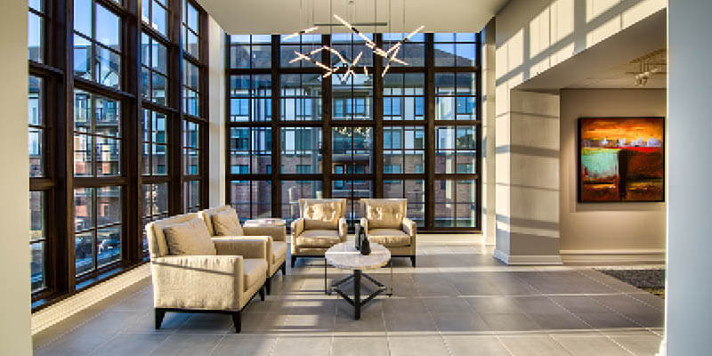 contemporary foyer area of a senior living community with tall windowed walls and seating area 2
