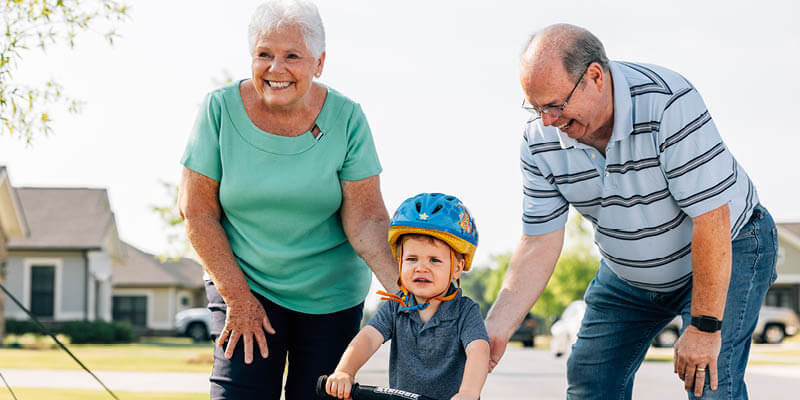Older couple helping their grandson ride a bike