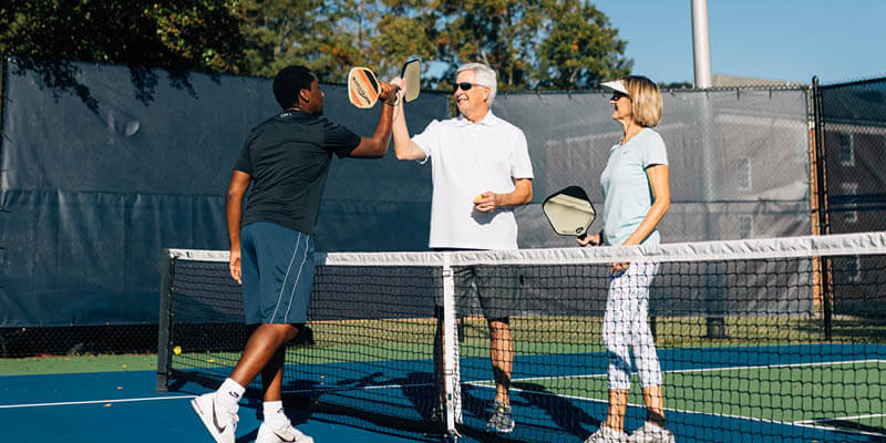 Pickleball opponents high-fiving each other over the net before a game