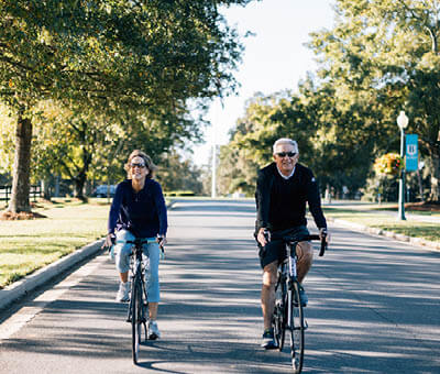 older man and woman riding bicycles down the street